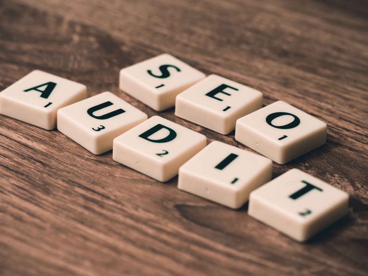 Lettres de Scrabble formant « audit SEO » posées sur une table en bois