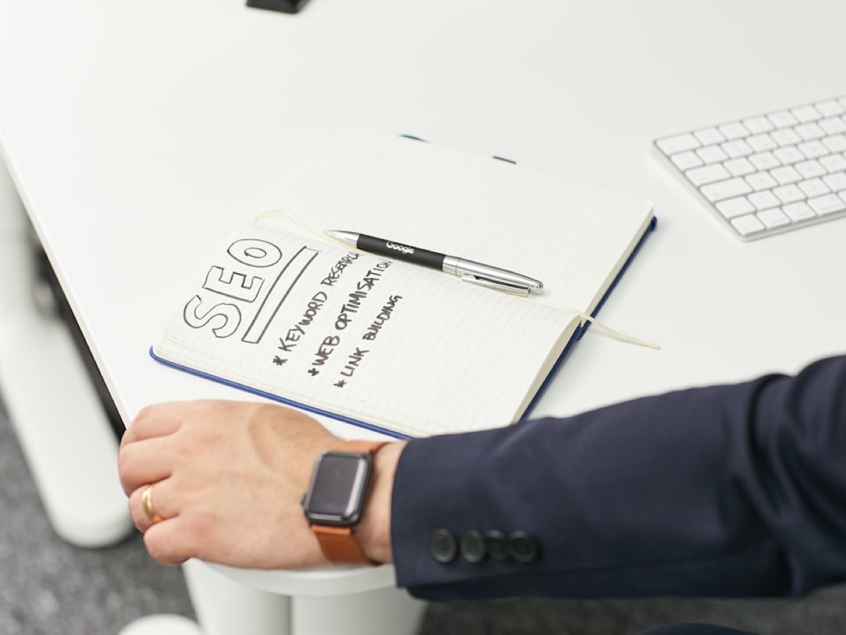 Consultant rédigeant une liste d'exigences SEO dans un carnet, geste du cahier des charges SEO