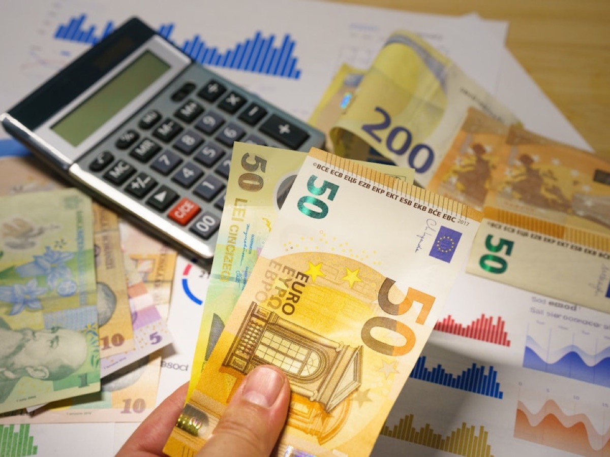 Main tenant des billets en euros près d'une calculatrice et de graphiques, mesure du ROI d'un consultant SEO e-commerce