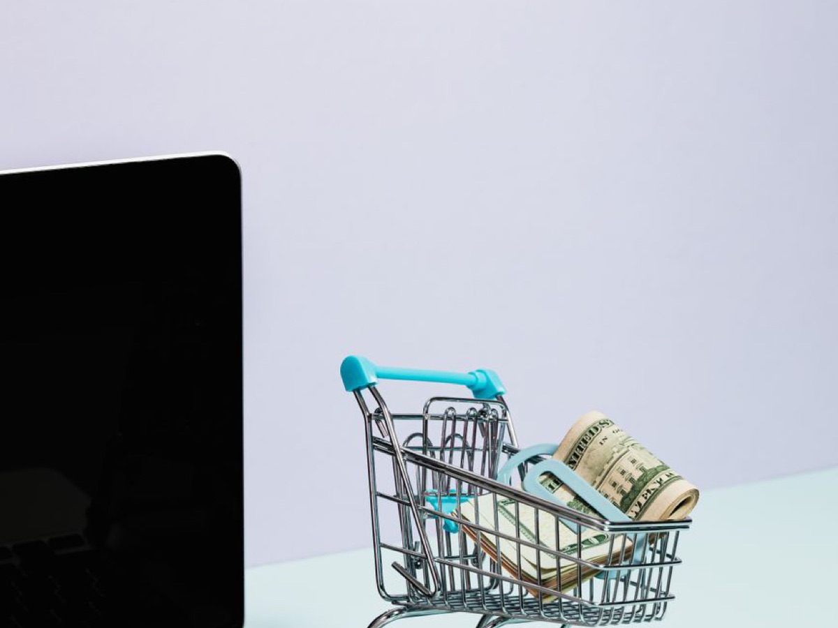 Panier d'achat miniature rempli de pièces sur un ordinateur portable, image du SEO e-commerce pour boutique en ligne