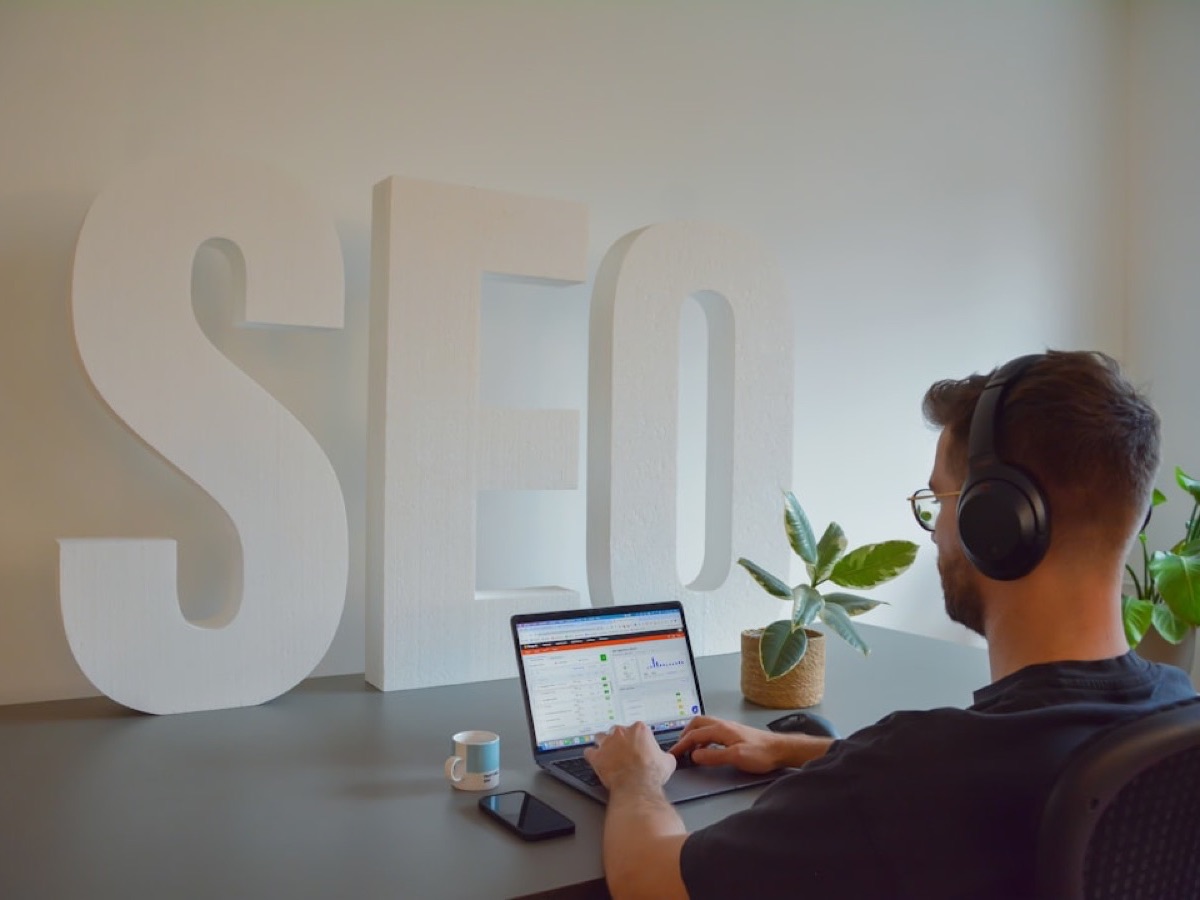 Consultant au casque travaillant sur ordinateur devant de grandes lettres SEO, contenu et maillage WordPress