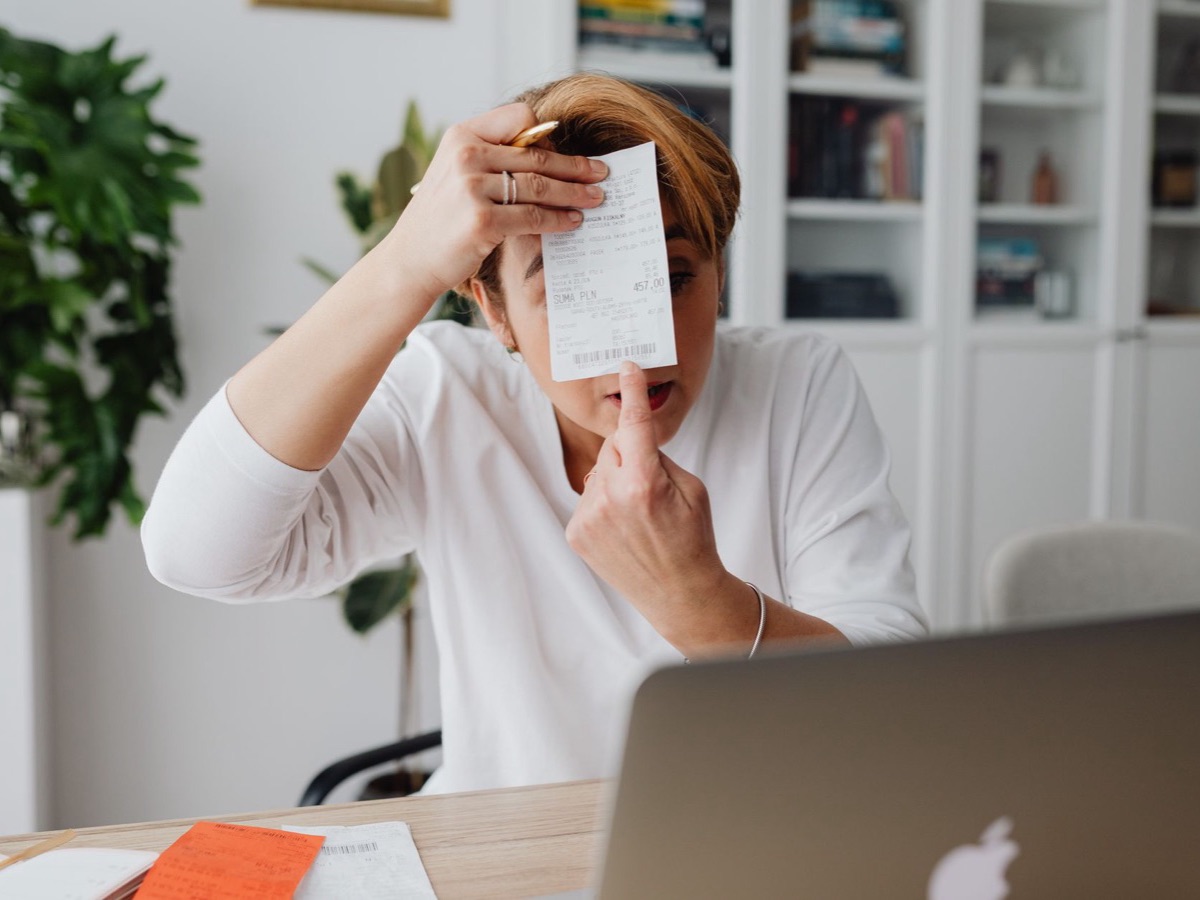 Femme surprise face à une facture à son bureau, ce qui fait varier le prix du référencement Google